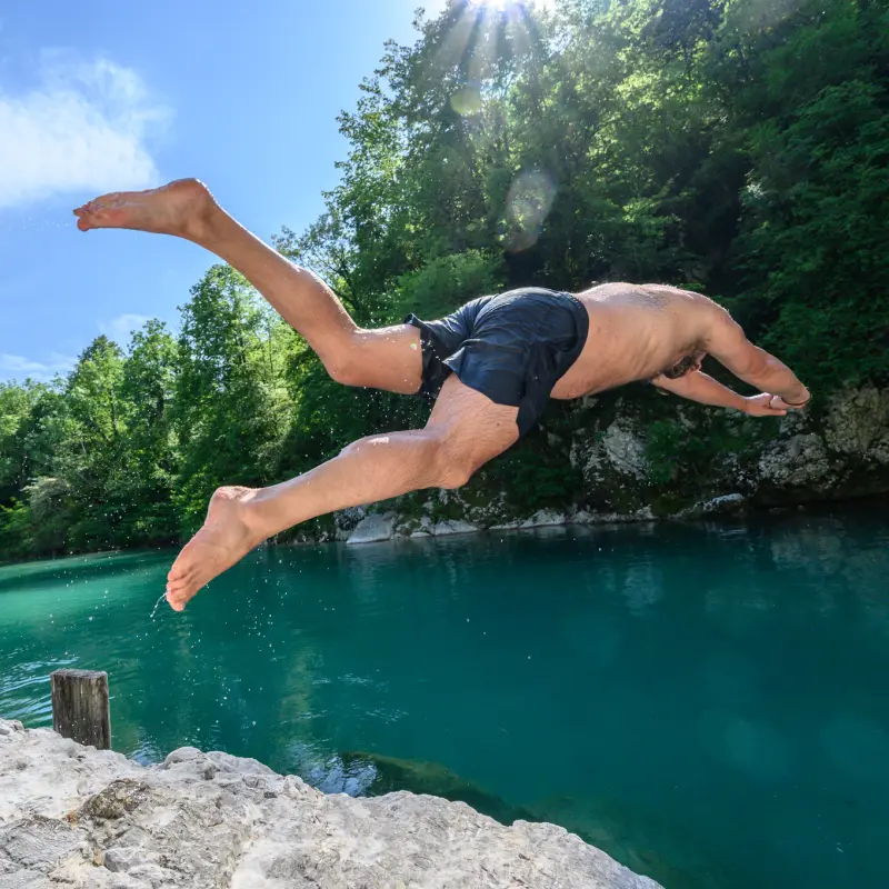 Ein Teilnehmer springt in einen türkisen Naturpool